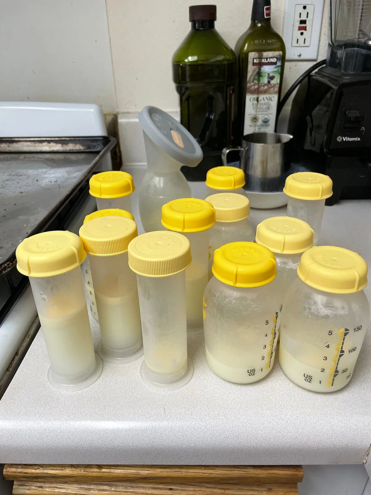 Plastic bottles with yellow caps, filled with human milk, sitting grouped on a counter.