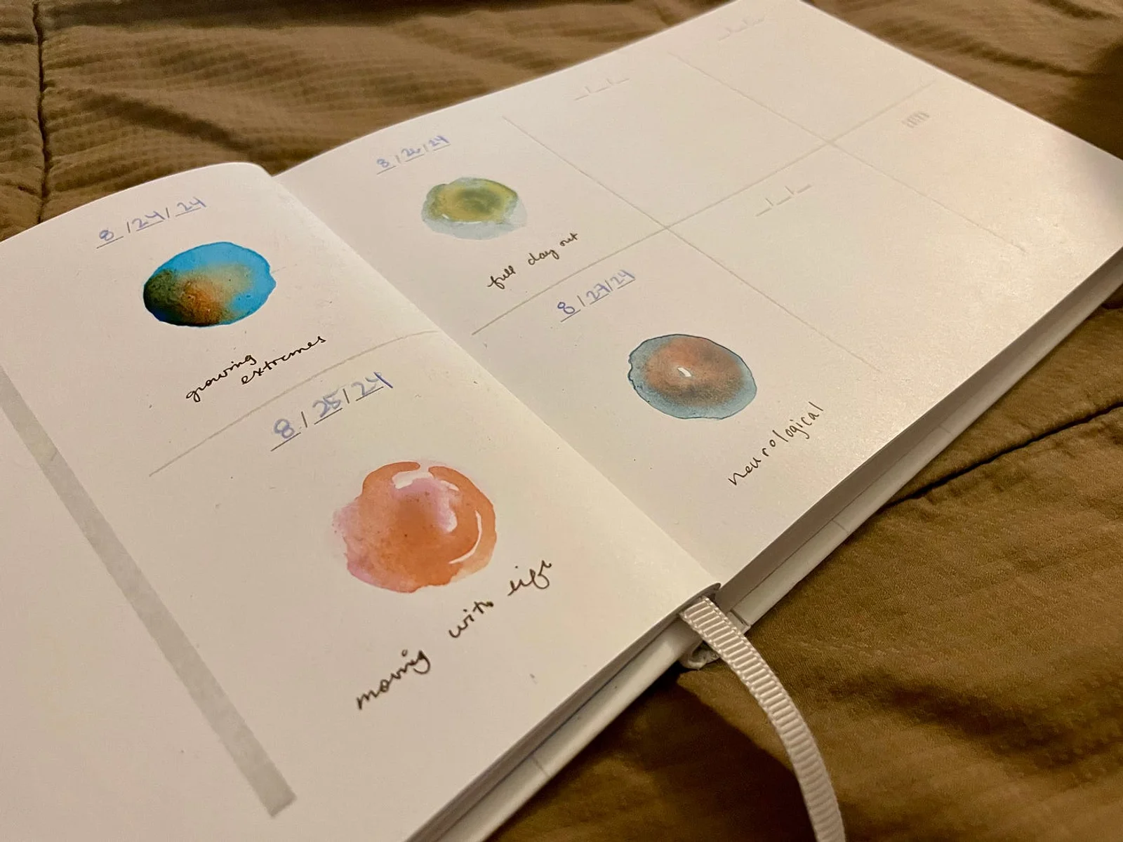 A book laying open, showing four circular swatches of watercolor paint in different color combination.