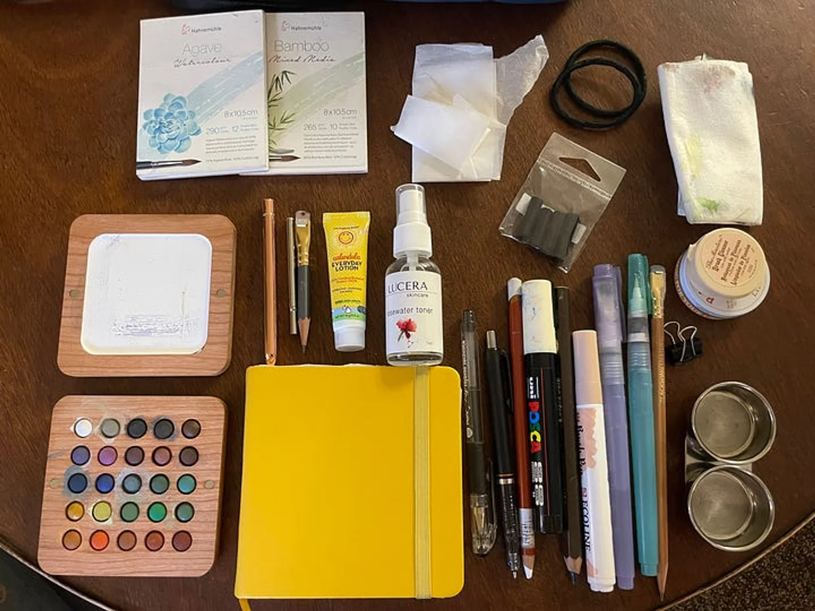 Various art supplies laid out on a table, and the bag they fit inside.