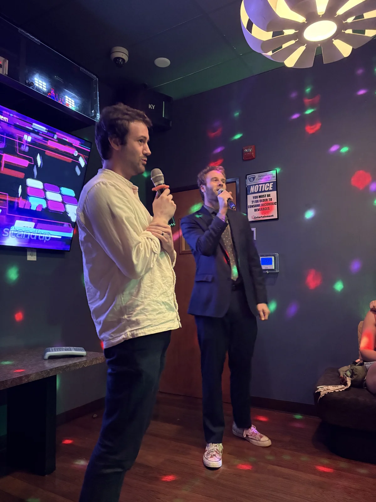 Two young men sing karaoke together.